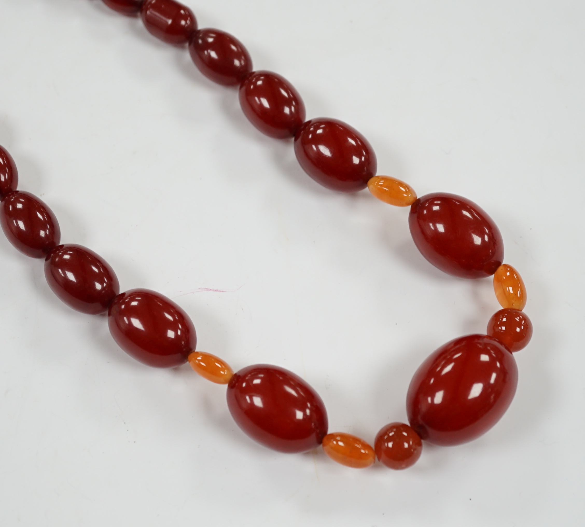 A single strand graduated simulated cherry amber bead necklace, with four simulated orange amber beads, 66cm, gross weight 84 grams.